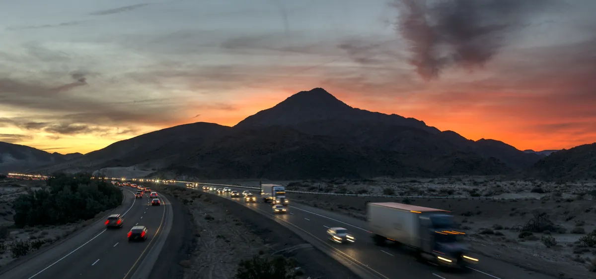Camión de carga en la carretera bajo el cielo rojo del atardecer